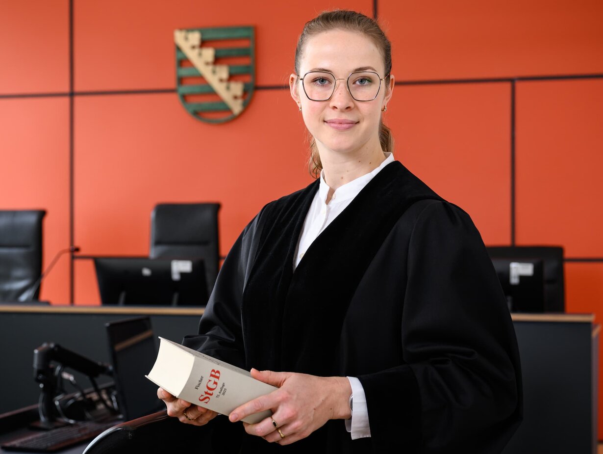 Eine junge Staatsanwältin im Gerichtssaal mit einem Gesetzbuch in der Hand