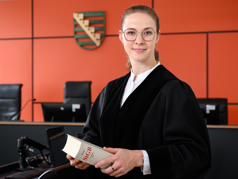 Eine junge Staatsanwältin im Gerichtssaal mit einem Gesetzbuch in der Hand