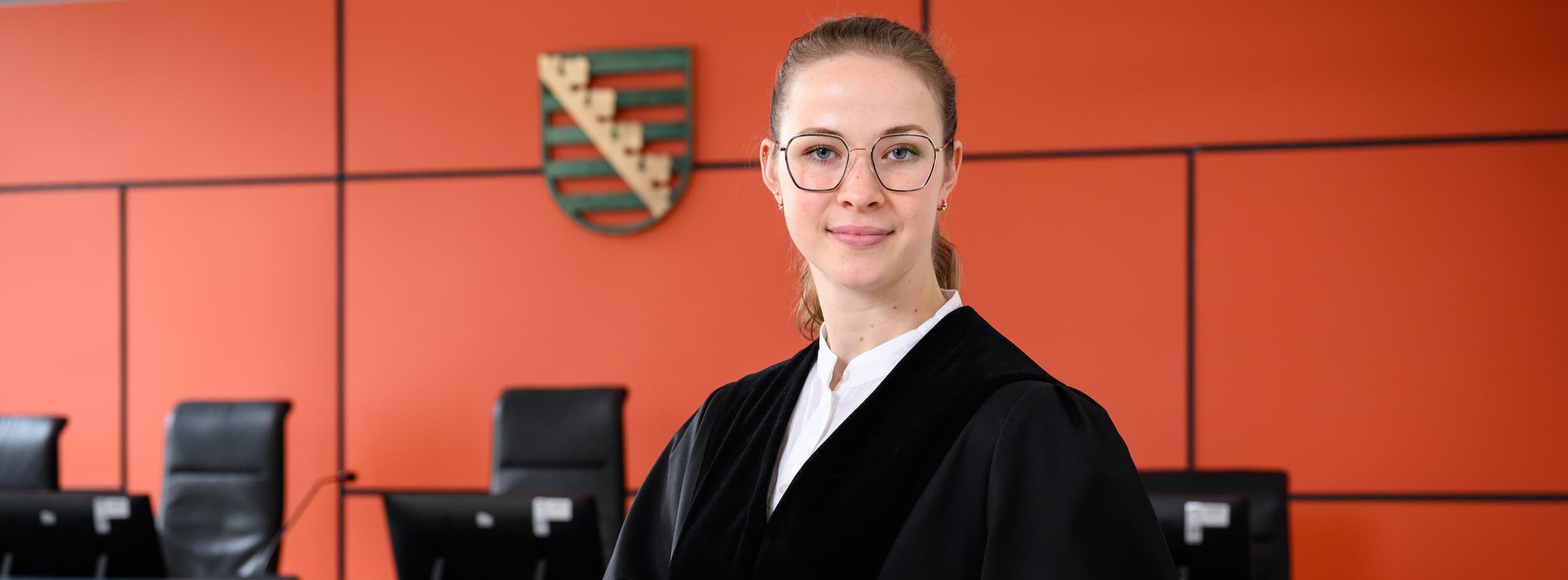 Eine junge Staatsanwältin im Gerichtssaal mit einem Gesetzbuch in der Hand