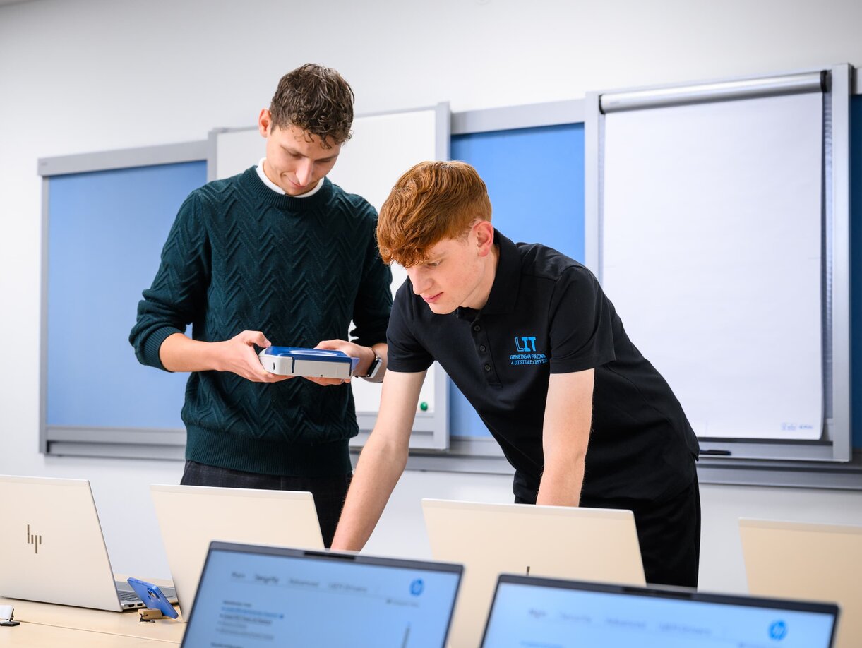 Zwei Mitarbeiter der Leitstelle für IT bei der Einrichtung von Notebooks in einem Schulungsraum