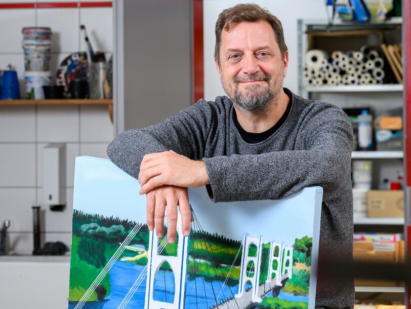 Ein Mitarbeiter des Kreativzentrumes im Justizvollzug hinter einem Bild