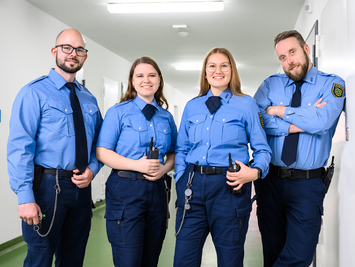 Vier Justizvollzugsbeamte stehen im Gang des Justizvollzugs