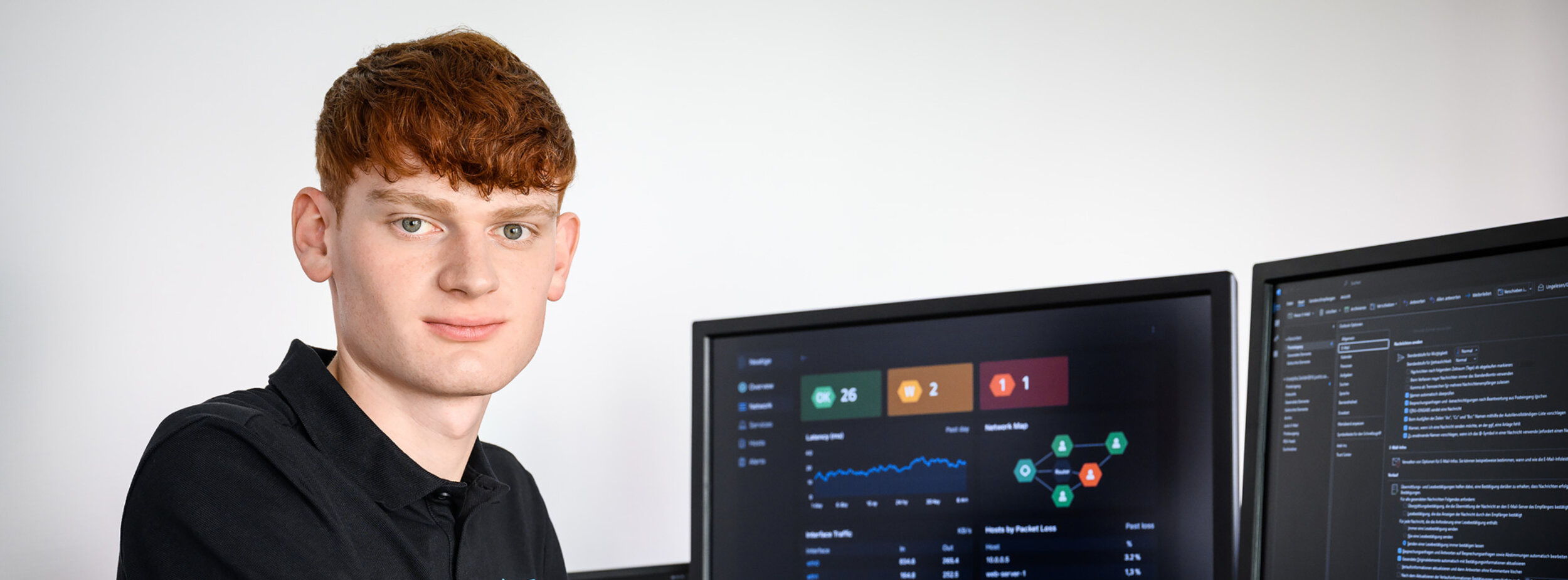 Ein Mitarbeiter der Leitstelle für IT an einem Schreibtisch mit Monitoren zur Überwachung der Systeme