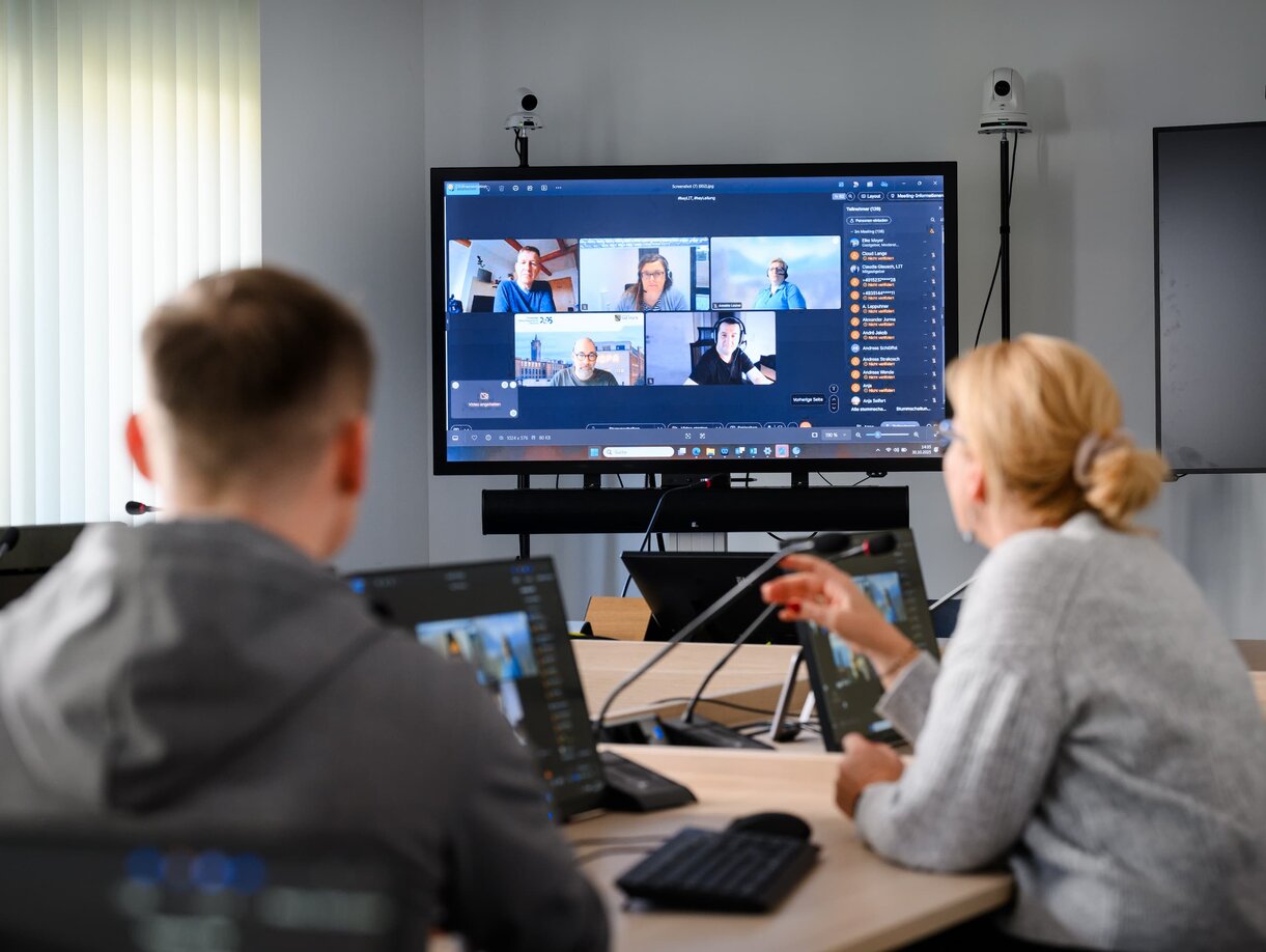 Ein Mitarbeiter und eine Mitarbeiterin der Leitstelle für IT bei einer Videokonferenz