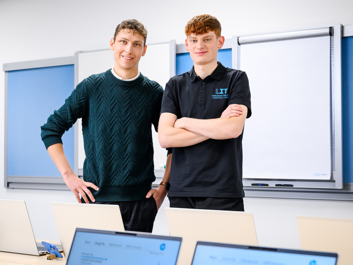 Zwei Mitarbeiter der Leitstelle für IT stehen in einem Schulungsraum