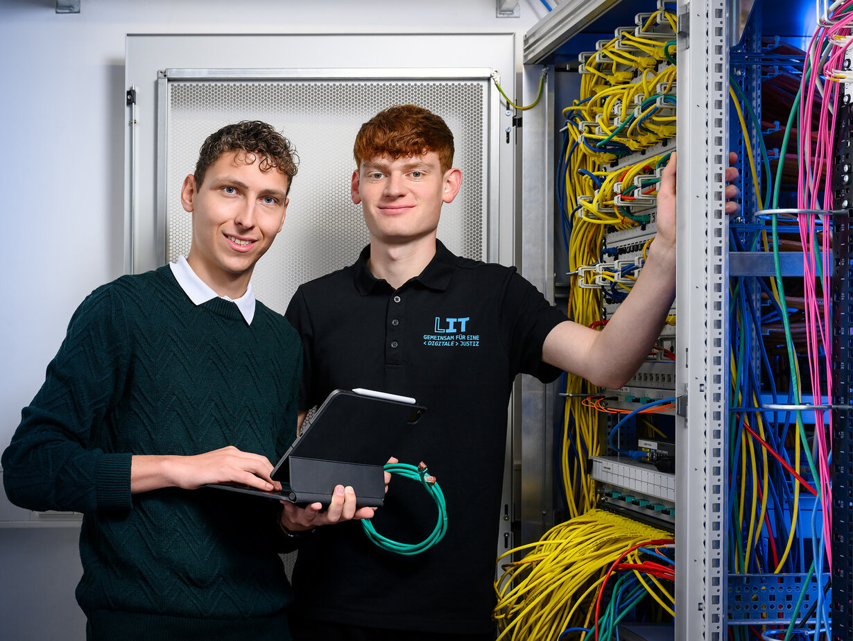Zwei Mitarbeiter der Leitstelle für IT an einem Schaltschrank