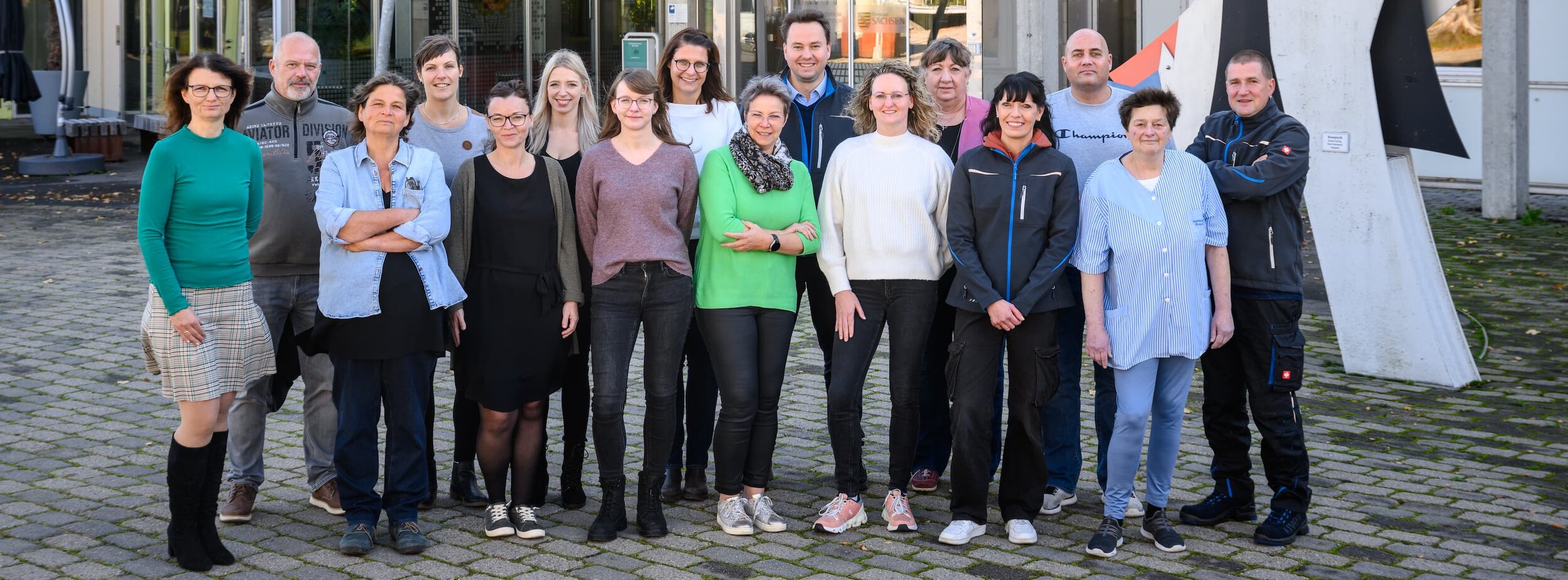 Mitarbeiter des Ausbildungszentrums stehen vor dem Eingang des Ausbildungszentrums