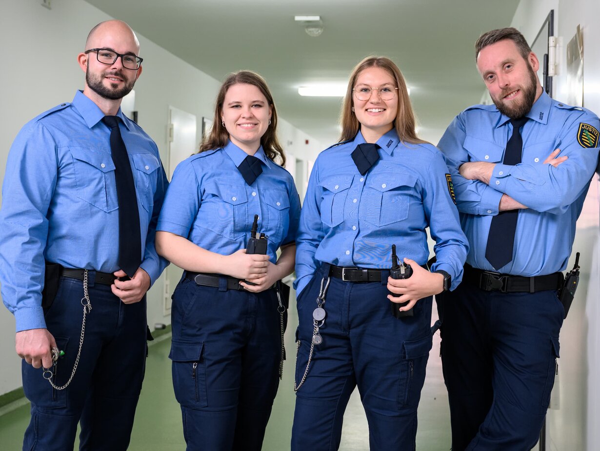 Vier Justizvollzugsbeamte stehen im Gang des Justizvollzugs