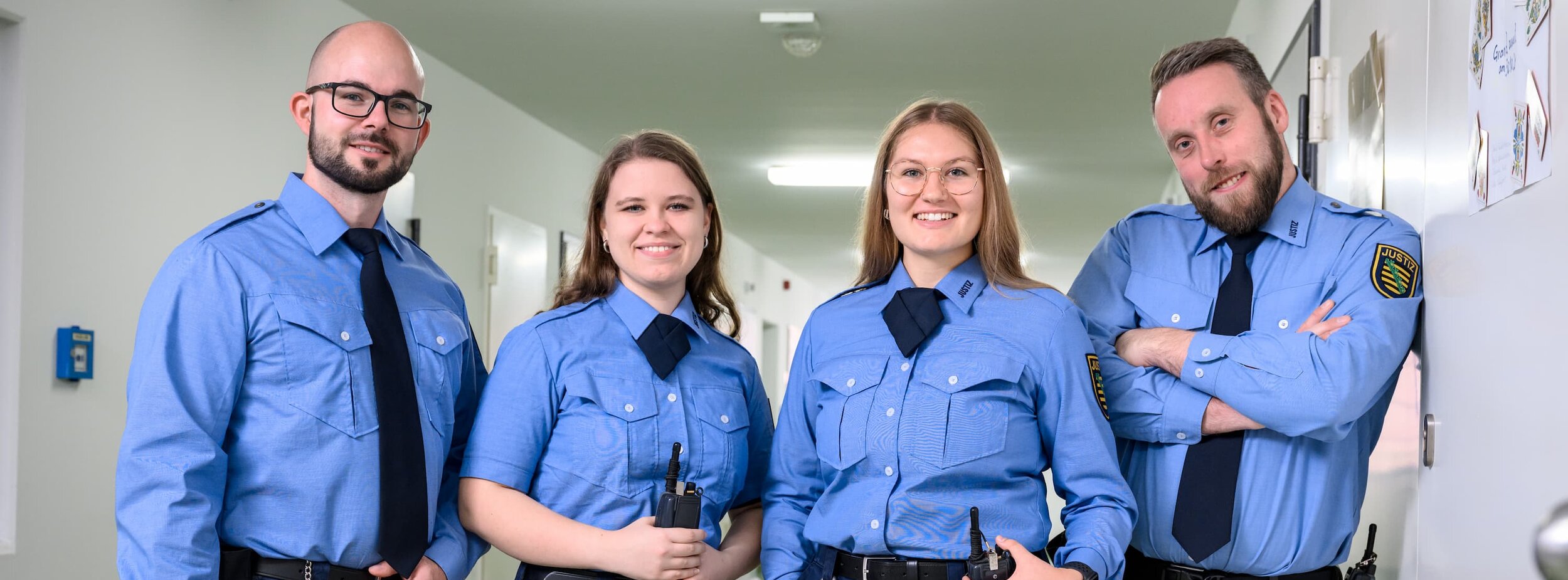 Vier Justizvollzugsbeamte stehen im Gang des Justizvollzugs