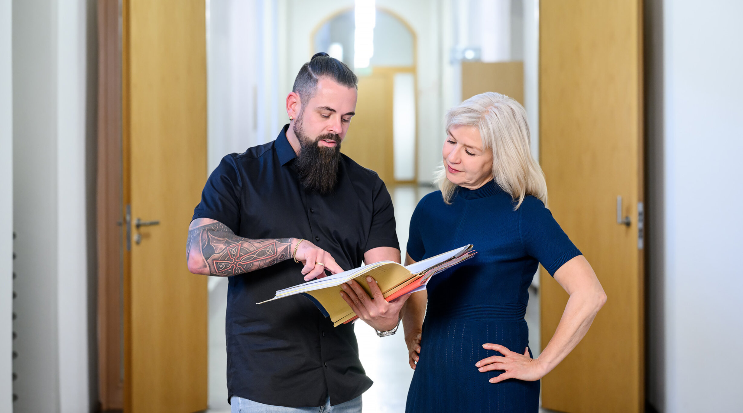 Ein Justizsekretär und eine Justizsekretärin im Gespräch; der Justizfachwirt zeigt etwas in einer Akte