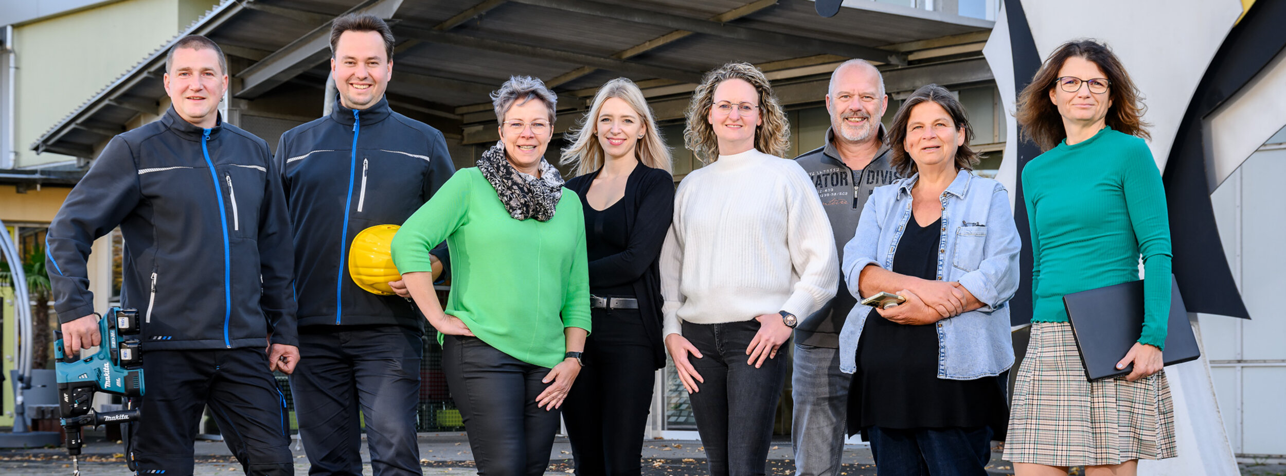 Mitarbeiter des Ausbildungszentrums stehen vor dem Eingang des Ausbildungszentrums