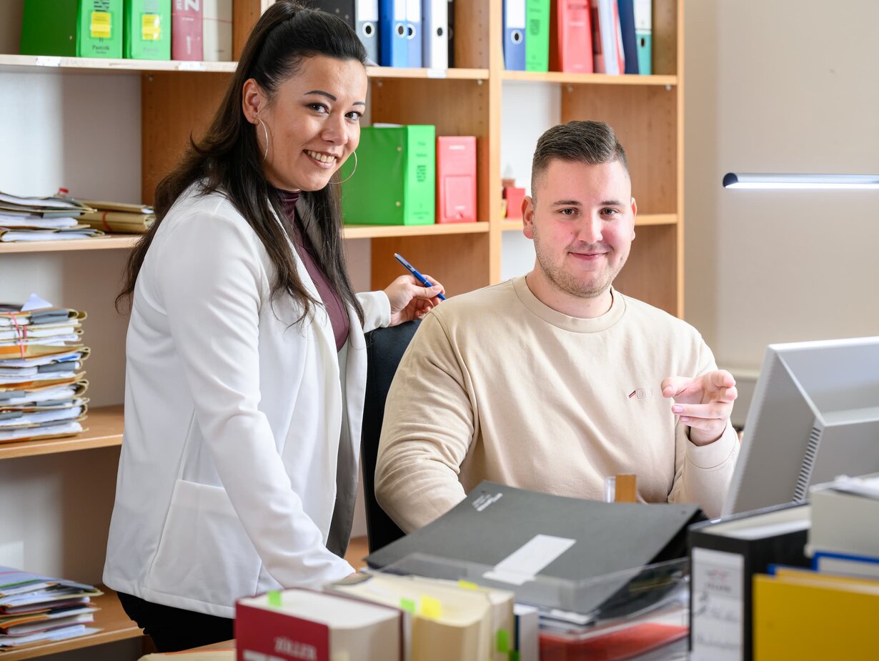 Eine Justizfachwirtin und ein Justizfachwirt im Gespräch am Schreibtisch