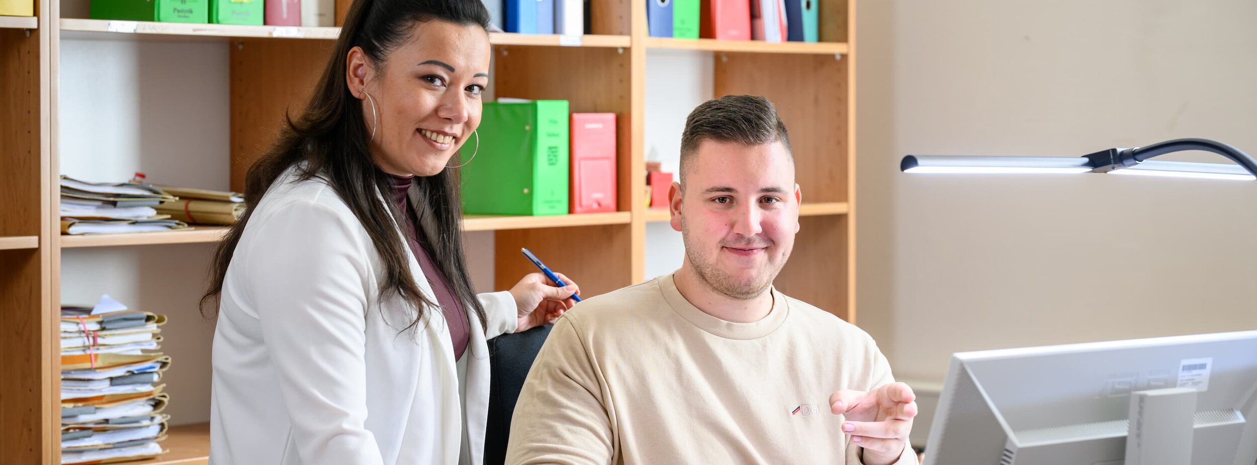 Eine Justizfachwirtin und ein Justizfachwirt im Gespräch am Schreibtisch