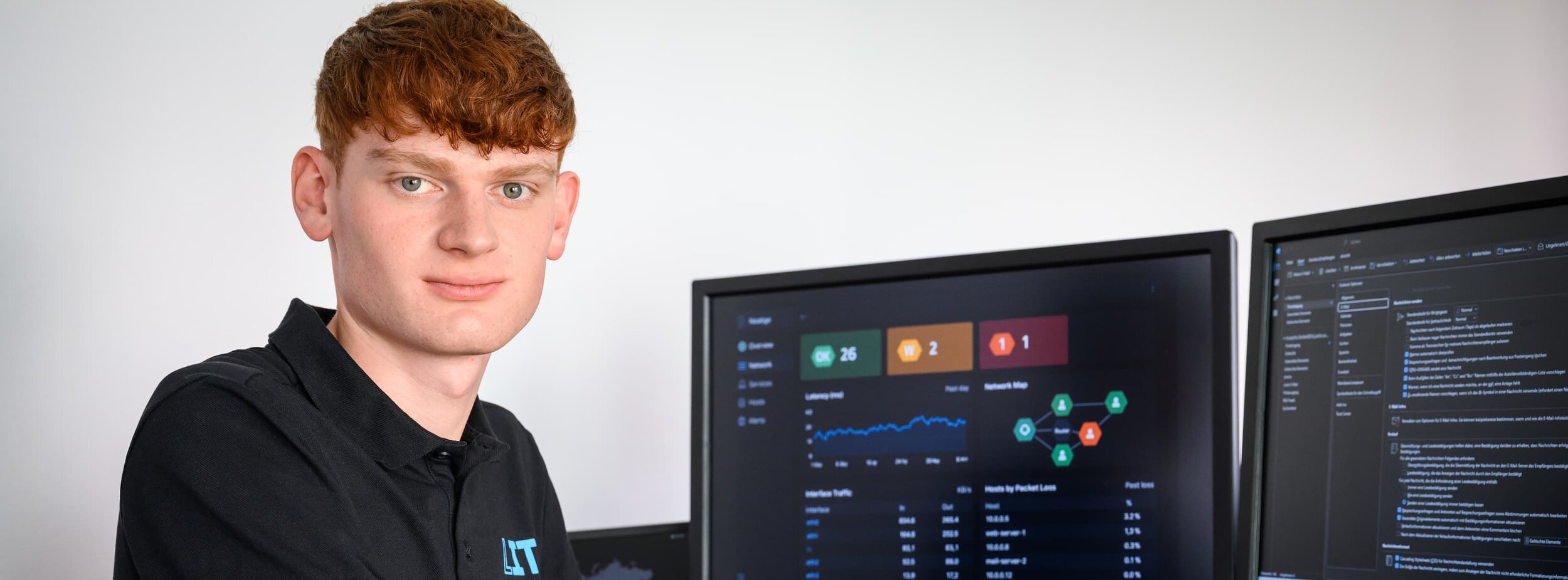 Ein Mitarbeiter der Leitstelle für IT an einem Schreibtisch mit Monitoren zur Überwachung der Systeme