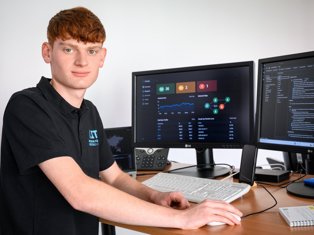 Ein Mitarbeiter der Leitstelle für IT an einem Schreibtisch mit Monitoren zur Überwachung der Systeme