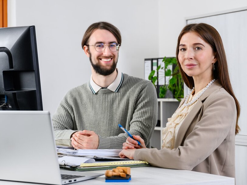 Ein Mitarbeiter und eine Mitarbeiter des Verwaltungsdienstes im Justizvollzug an einem Schreibtisch