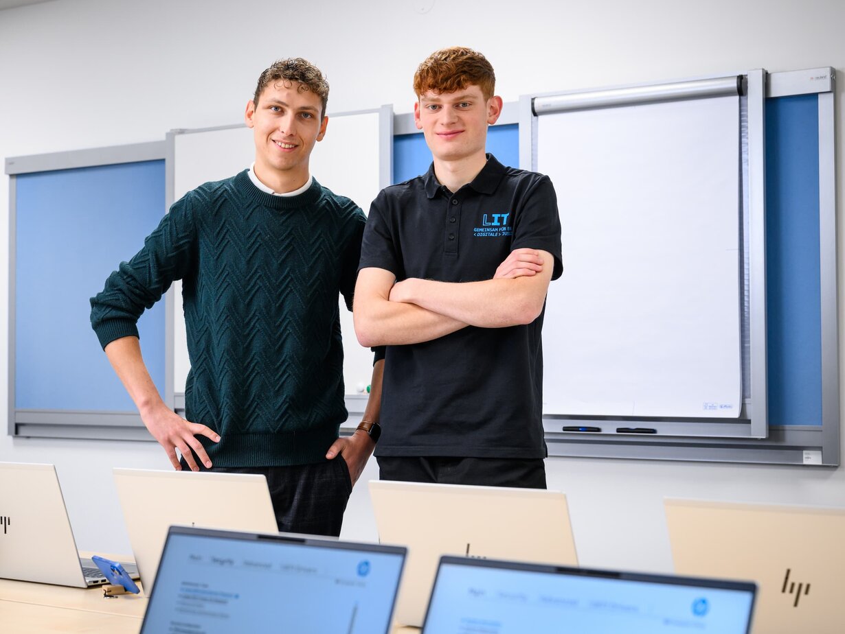 Zwei Mitarbeiter der Leitstelle für IT stehen in einem Schulungsraum