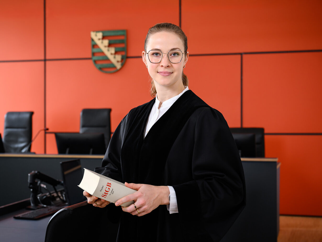 Eine junge Staatsanwältin im Gerichtssaal mit einem Gesetzbuch in der Hand