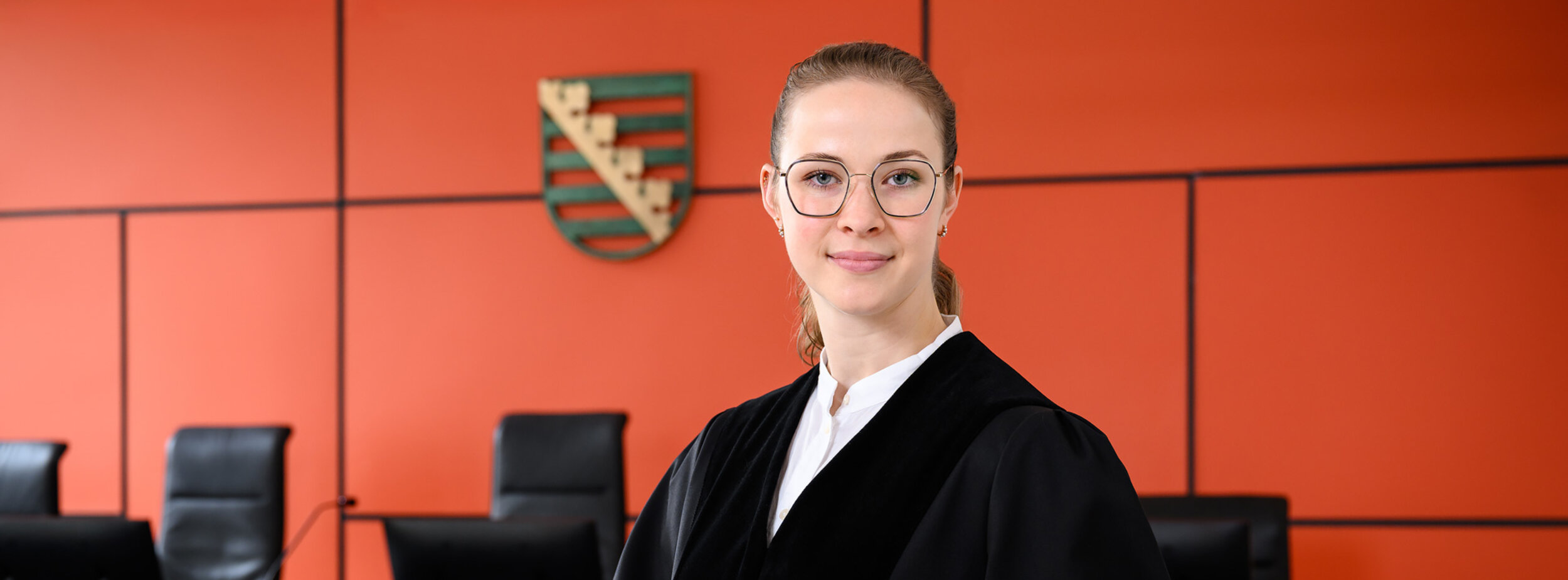 Eine junge Staatsanwältin im Gerichtssaal mit einem Gesetzbuch in der Hand