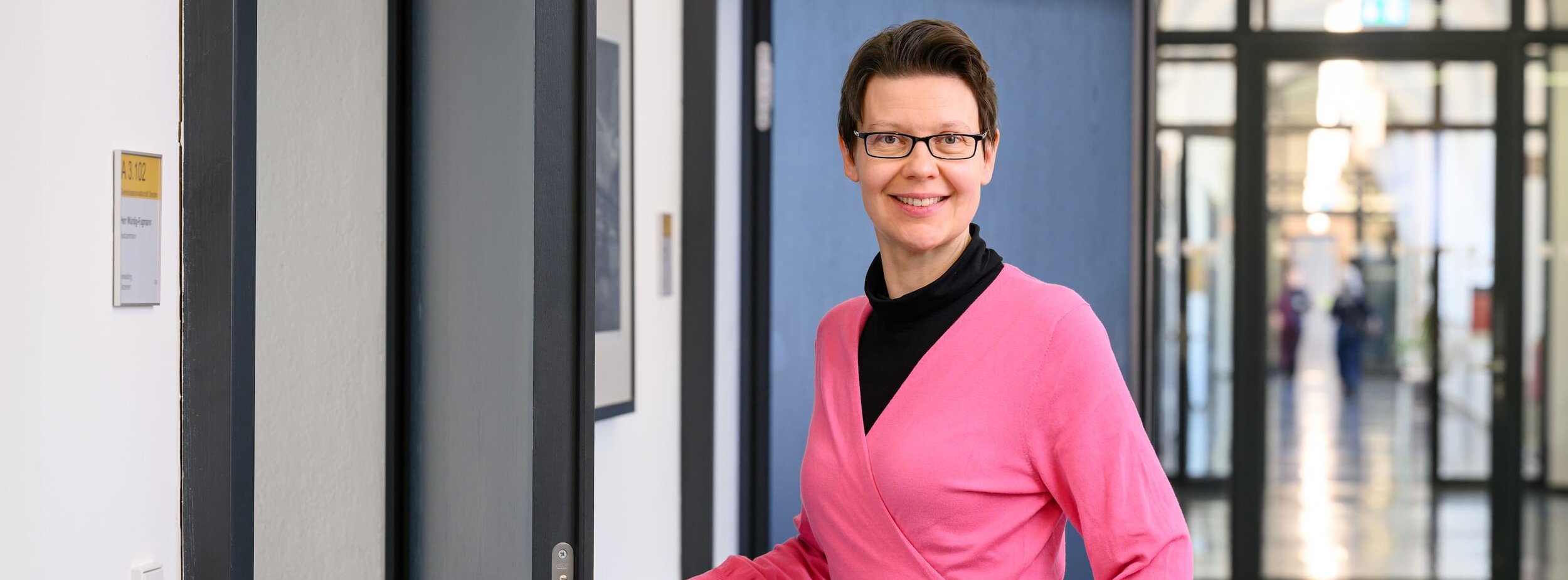 Eine Wirtschaftsreferentin auf dem Gang öffnet eine Tür im Gerichtsgebäude